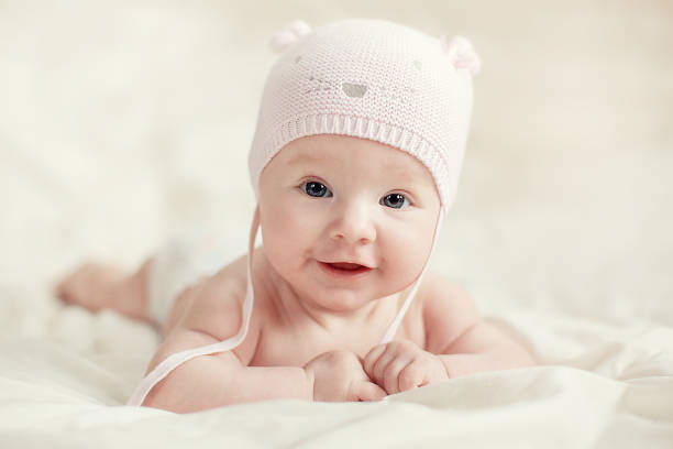Newborn Baby Girl In Pink Knitted Hat On A Bed.