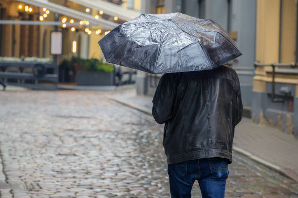 Man With An Umbrella In The City. Back View Of Busy Man In Rainy Weather